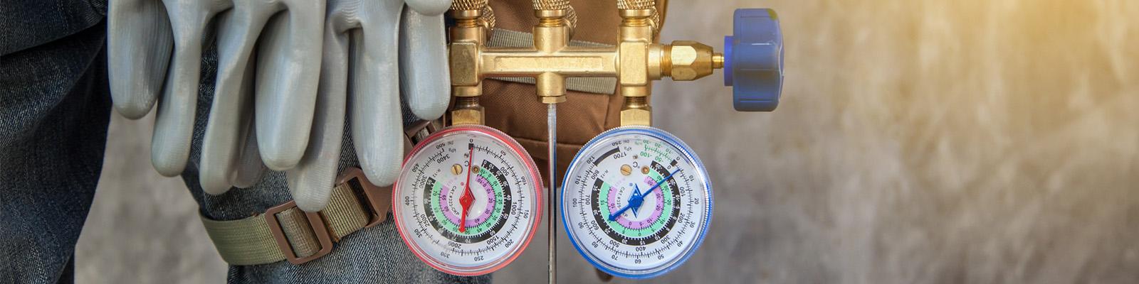 This is a closeup of an HVAC technician's work gloves and temperature gages.
