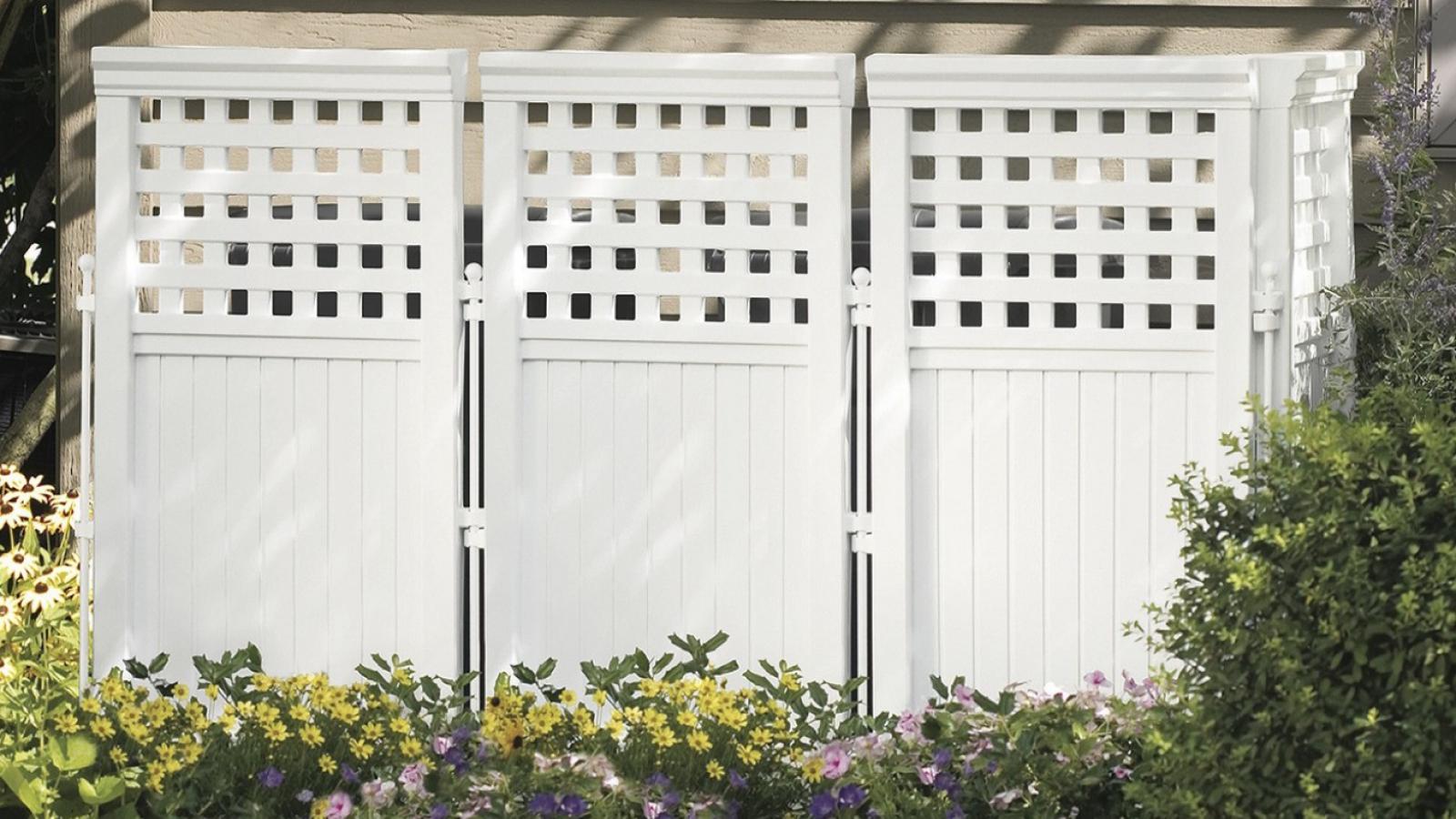 A tall, aesthetically-pleasing white fence conceals an outdoor HVAC unit.