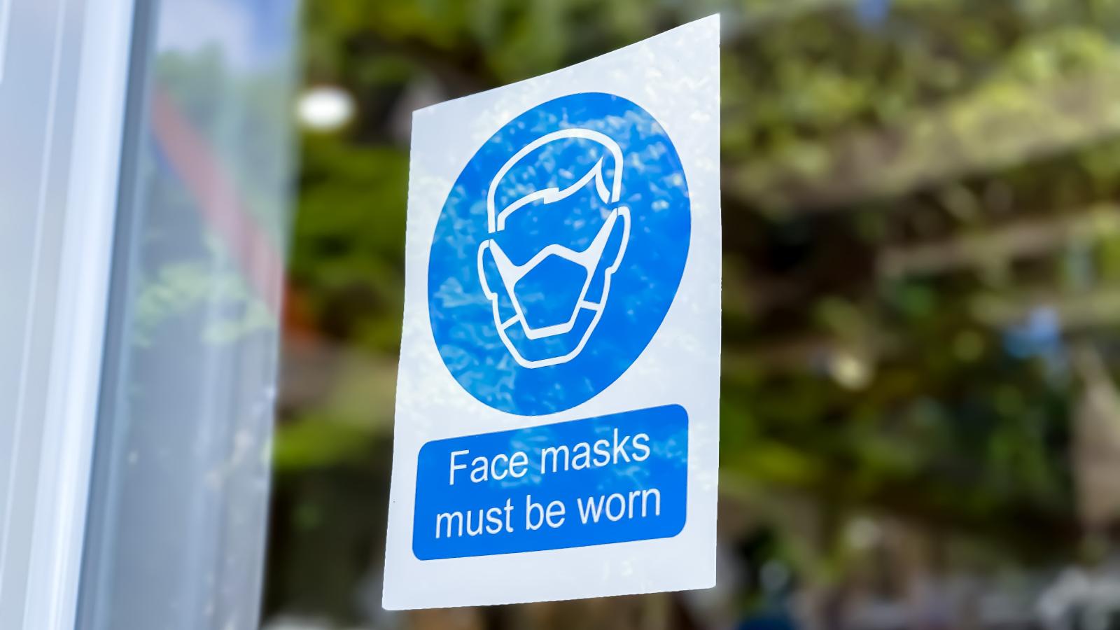 A blue sign that reads Face Masks with an image is displayed in a window.