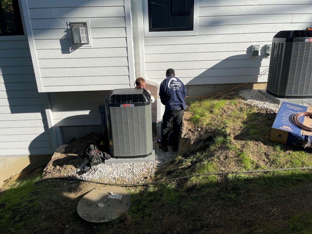 Two HVAC technicians work on an outdoor Trane HVAC system.