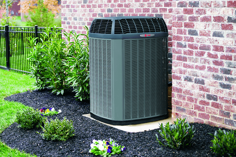 A Trane air conditioner against a brick wall.