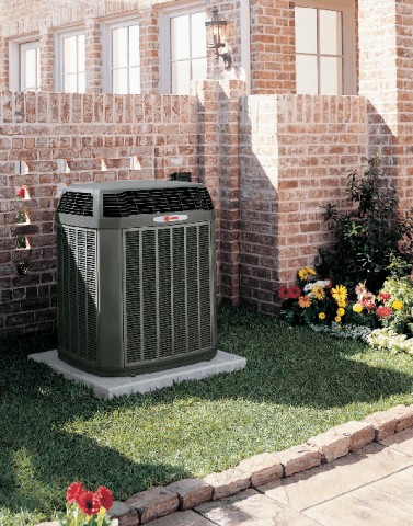 A Trane air conditioner system outside of a home with brick walls.
