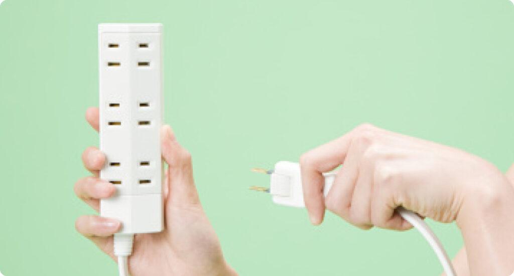 A person holding a power strip, which can be used to save energy