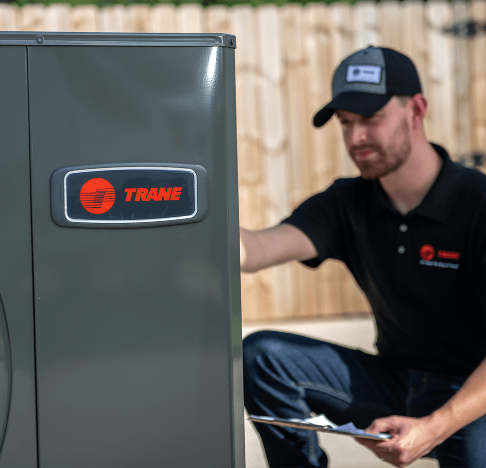 An hvac technician is checking a heat pump outside.