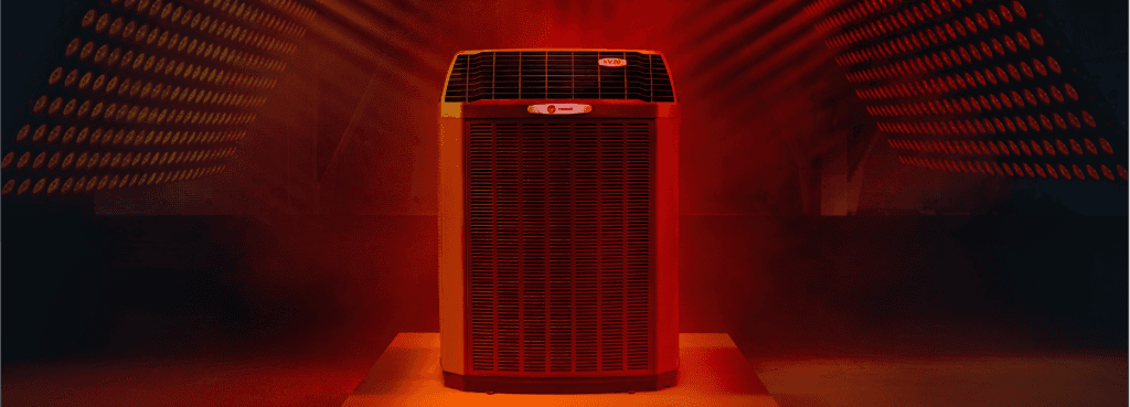 A Trane indoor unit is displayed on a platform in a room with red lights and fog.
