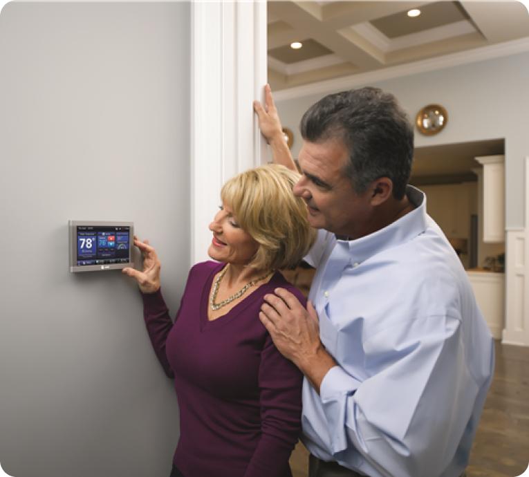 A couple program their smart thermostat to provide increased energy efficiency.