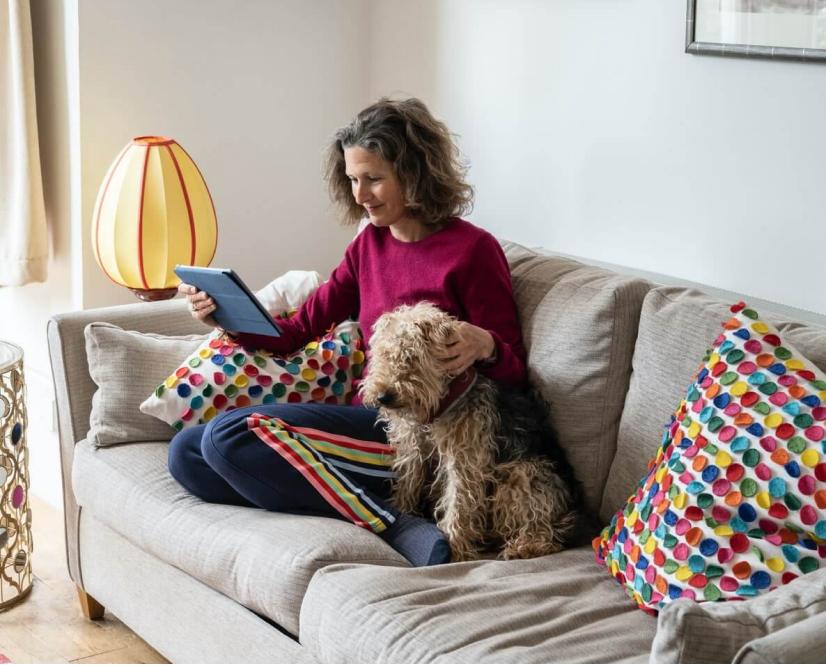 A woman relaxing on her sofa with her dog.