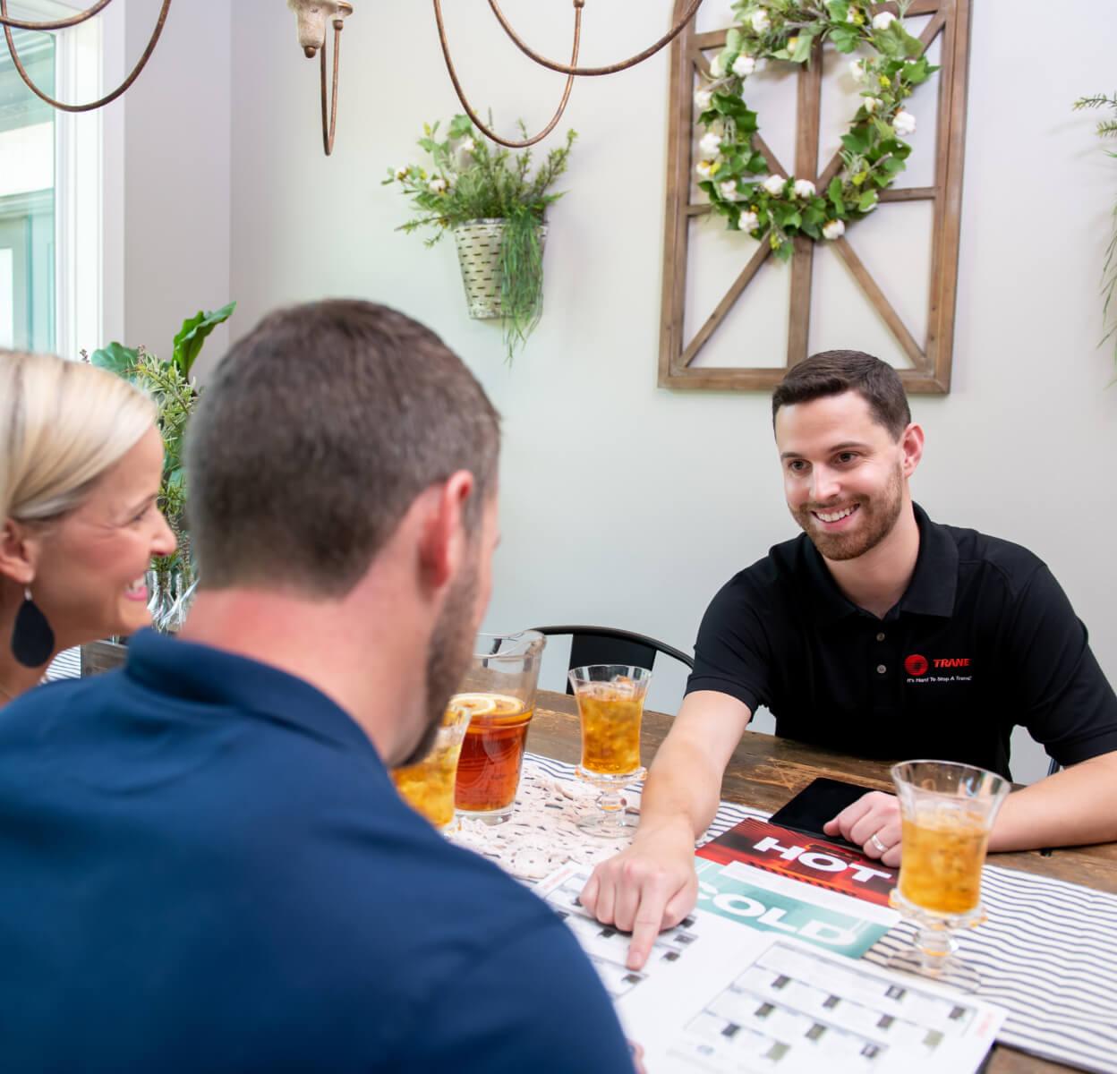 An HVAC dealer showing documentation to a couple in their home.