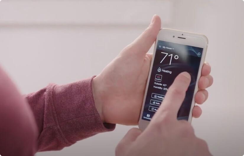 A person using a smart phone to check their home temperature.