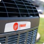 A Trane air conditioner with close up of red logo.