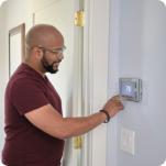 A man using a smart thermostat in his home