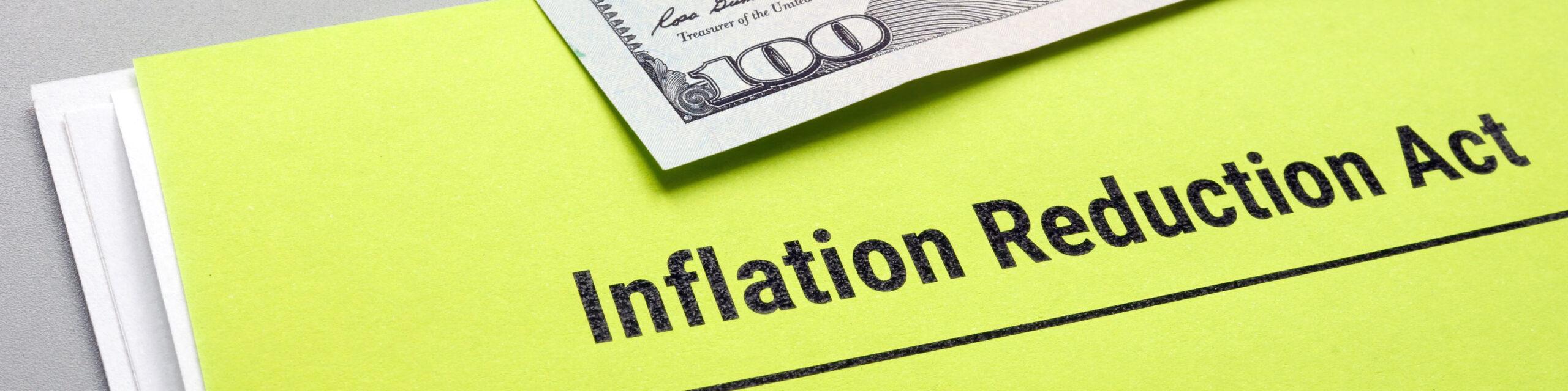 A bright yellow folder with the text "Inflation Reduction Act" and a 100-dollar bill.