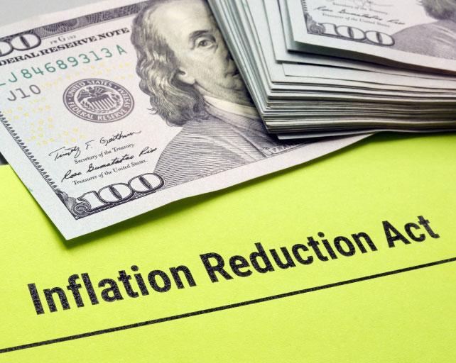 A bright yellow folder with the text "Inflation Reduction Act" and a 100 dollar bill.