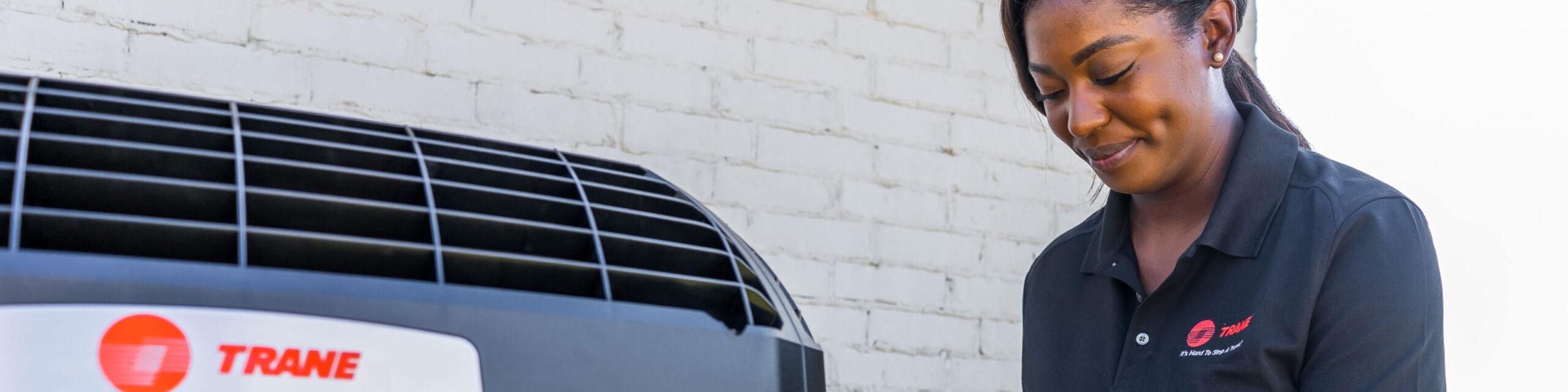 Female Trane technician maintaining HVAC system.