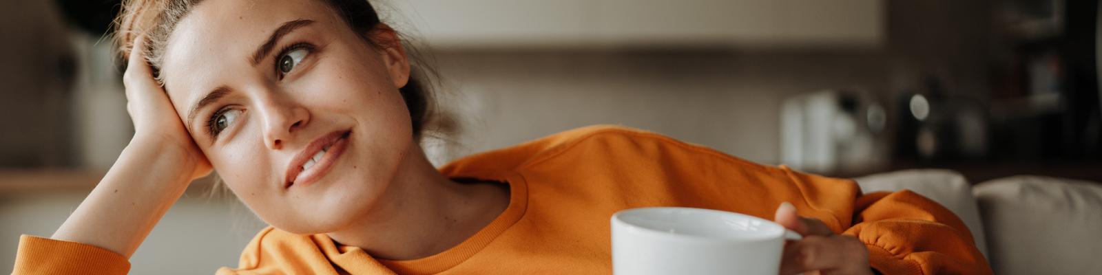 woman sitting on couch in home contemplating heat pump vs furnace