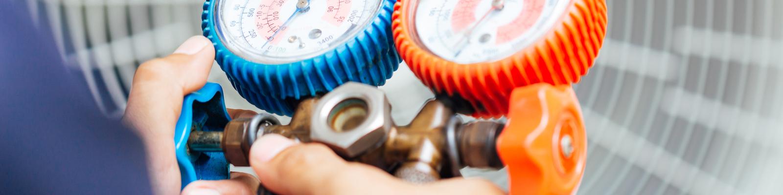 This is a closeup image of an HVAC technician holding temperature gages.
