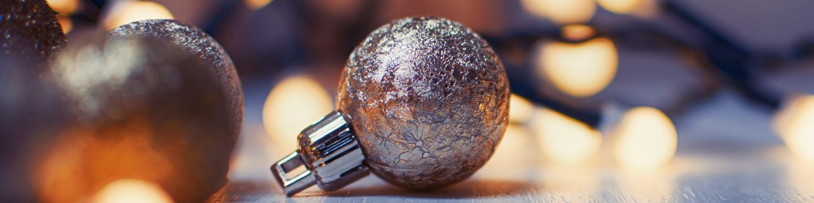 There is a shiny metallic , round Christmas ornament with lights around it.