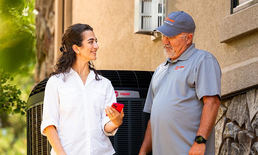 A female homeowner is outside with a Trane dealer.