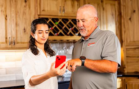 Trane comfort specialist is showing a woman the HVAC Performance Kit on her phone.