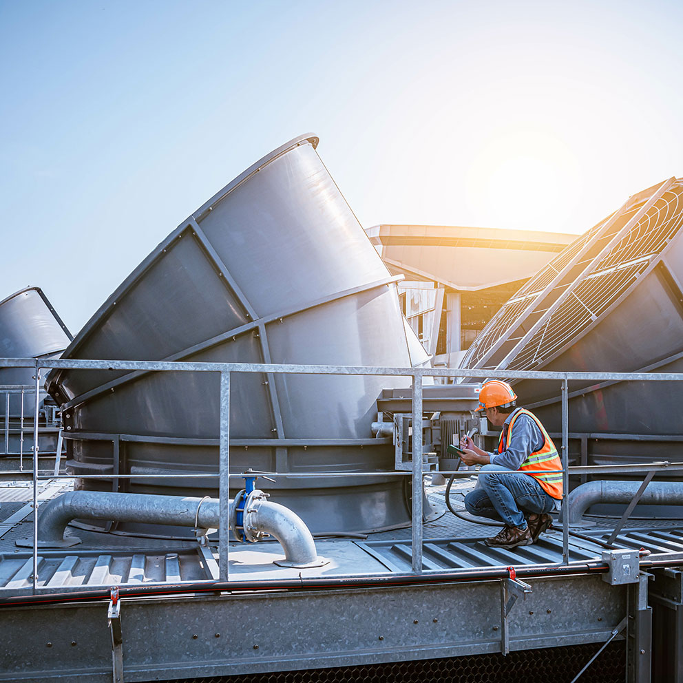 A engineer under checking the industry cooling tower air conditioner is water cooling tower air chiller HVAC of large industrial building to control air system.