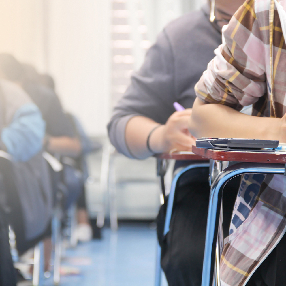 Hands university student holding pen writing /calculator doing examination / study or quiz, test from teacher or in large lecture room, students in uniform attending exam classroom educational school.