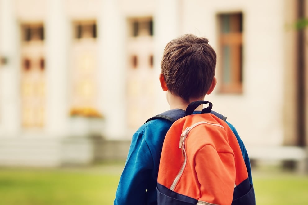 Boy with rucksack infront of a school building