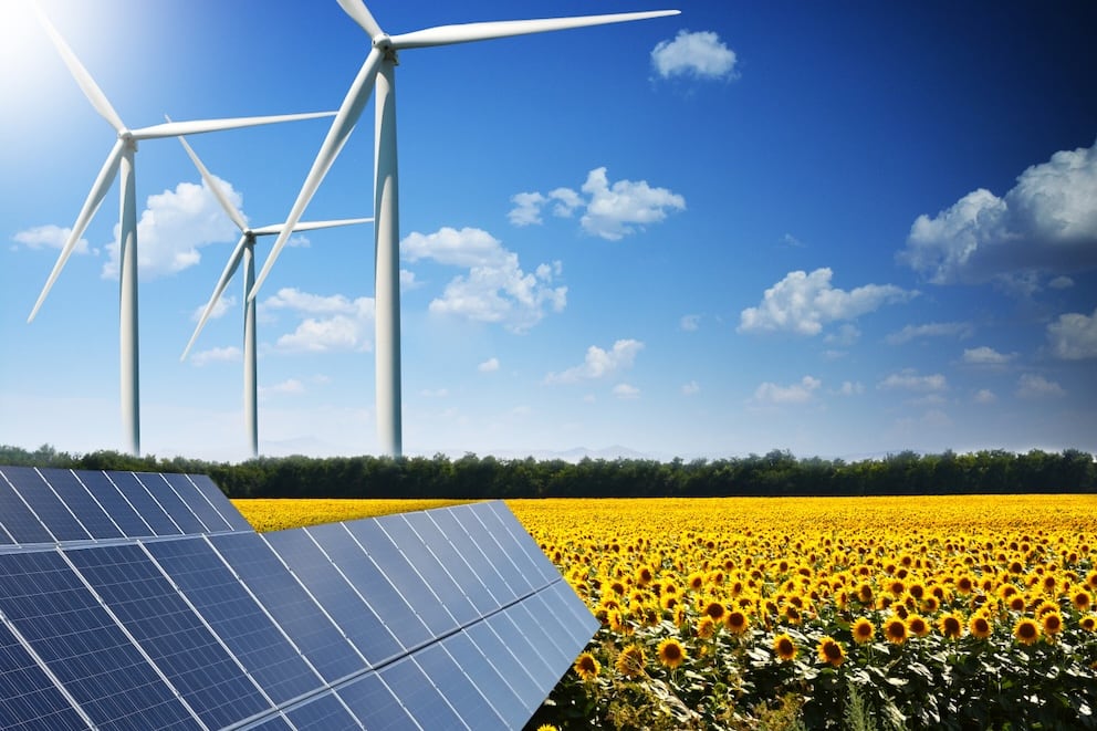 Green energy concept with solar panels and wind turbines on a sunflower field