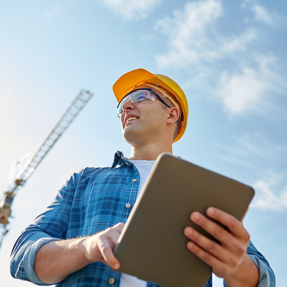 builder in hardhat with tablet pc at construction