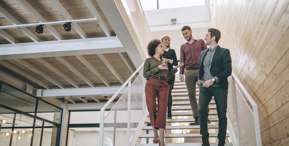 Young business people talking and walking down stairs