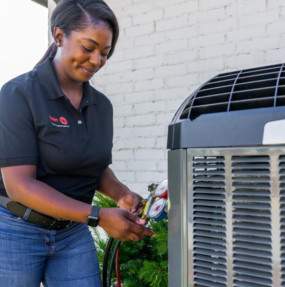A Trane HVAC technician takes a measurement from an air conditioner.